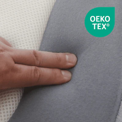 Gros plan sur la housse grise du Cocon avec le label OEKO-TEX, une main touche la matière